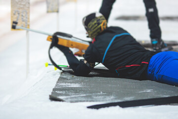 Biathlete with rifle on a shooting range during biathlon training, skiers on training ground in winter snow, athletes participate in biathlon competition on slope piste