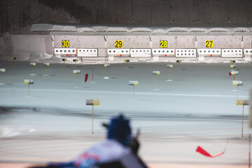 Biathlete with rifle on a shooting range during biathlon training, skiers on training ground in winter snow, athletes participate in biathlon competition on slope piste