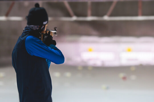 Biathlete with rifle on a shooting range during biathlon training, skiers on training ground in winter snow, athletes participate in biathlon competition on slope piste