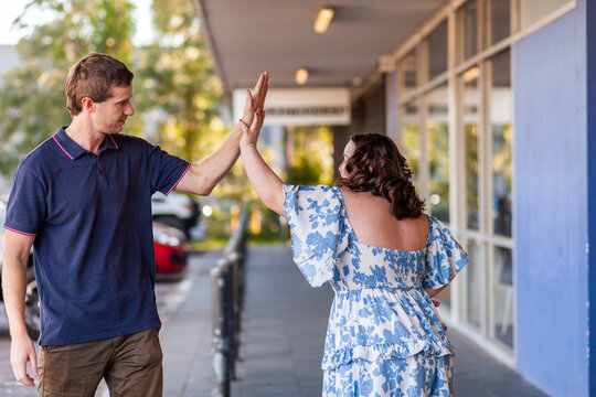 Young person with a disability giving support person a high five while outside shops