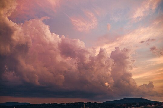 Fototapeta Big white clouds in the pink sunset sky with hill silhouettes underneath