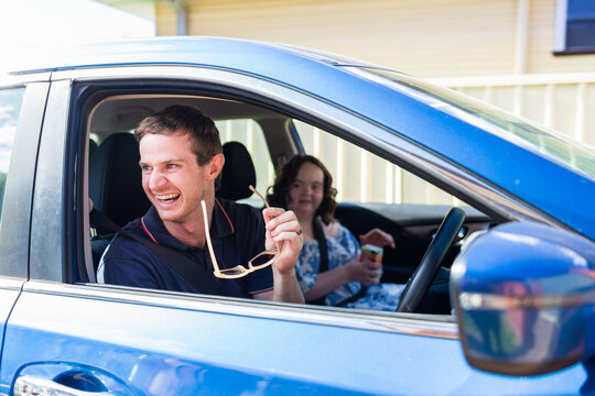 Happy male NDIS provider driving car laughing and assisting with transport within community