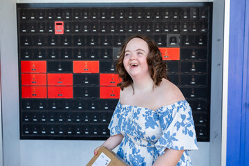 Happy young person with a disability holding brown box parcel near post office