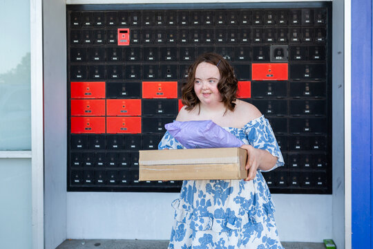 Happy young lady holding parcels with compostable packaging picked up from post office