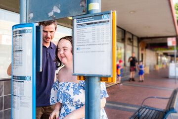 Disability worker NDIS provider helping young woman check bus time tables to catch public transport