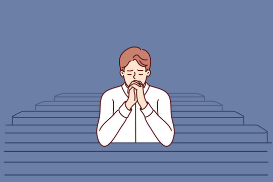 Christian man sits and prays in catholic church, turning to god to confess or ask for help. Believing guy in church and prays to feel psychological relief or observe religious ritual 