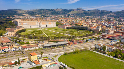 Fototapeta na wymiar Aerial view of the Royal Palace of Caserta also known as Reggia di Caserta. It is a former royal residence with large gardens in Caserta, near Naples, Italy. The historic center of the city is nearby.