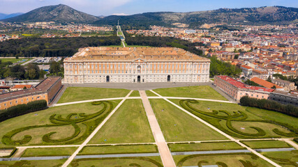 Aerial view of the Royal Palace of Caserta also known as Reggia di Caserta. It is a former royal residence with large gardens in Caserta, near Naples, Italy. It is the main facade of the building. - obrazy, fototapety, plakaty