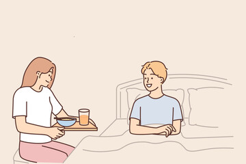 Caring wife brings breakfast to bed to beloved husband wanting to bring joy or caring during illness