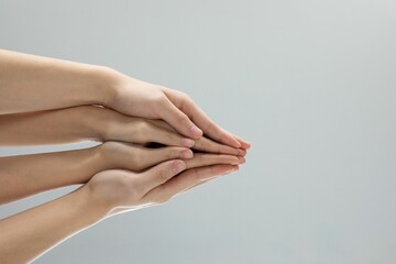 Closeup shot of helping hands touching in front of a gray background