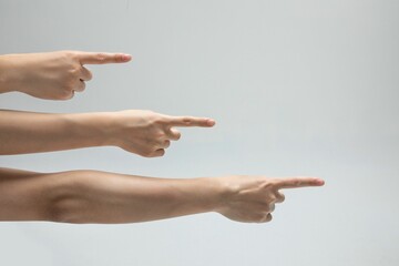 Closeup shot of a bunch of hands pointing to something on a gray background with copy space