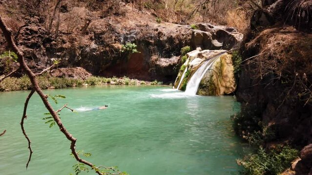 Adult man swimming in the lake of Cascada de Comala Park a sunny day in Chiquilistlan, Mexico