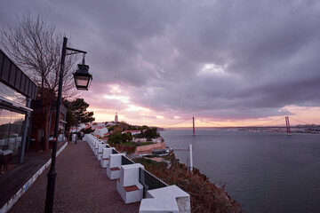 Terrace with wonderful view of suspension 25 April bridge bridge over the Tagus river in Lisbon at sunset.