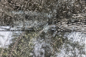 Broken windshield of a car close-up as a background. Texture broken glass with cracks.