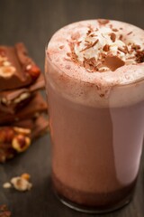 Vertical shot of hot chocolate with cream in a glass cup on a wooden table.