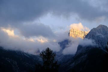Beautiful shot of clouds floating over snowy mountains in Madonna di Campiglio, Italy