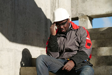 African american worker at project site has headache, he touches his head