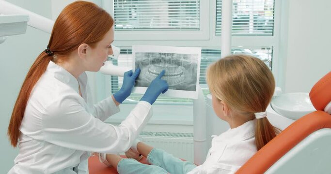 dentist female doctor shows a picture of the jaw to adorable young patient. The concept of a healthy lifestyle. slow motion health teeth care slow motion
