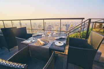 Table setting on roof top restaurant with megapolis view, Bangkok Thailand.