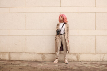 Portrait shooting of a stylish girl with pink hair. Beige shades. Trends of spring and summer 2023....