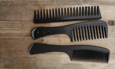 close-up of three black combs with large rare teeth for caring for mustaches and beards lie on old...