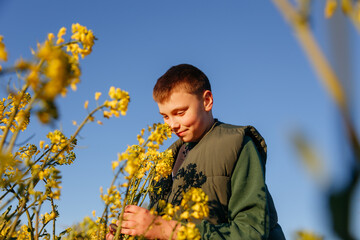 child sniffing flowers in a field against a blue sky