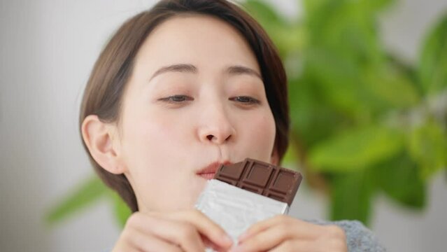 チョコレートを食べる若い女性　飲食イメージ	
