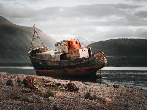 Horizontal view of an old wooden ship next to a shore in the river in Fort William, Scottland