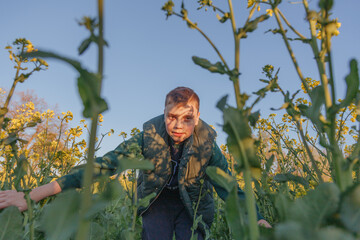 boy looks at the ground in a field of flowers