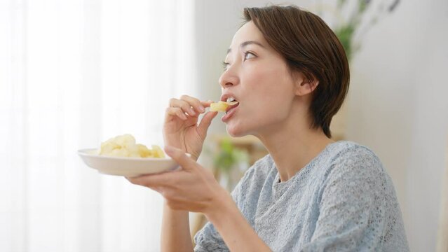 ポテトチップスを食べる若い女性　飲食イメージ	
