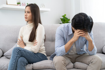 Fototapeta premium Family problems, Asian women cover her face and sit separately from husband feel disappointed after quarrels at home.
