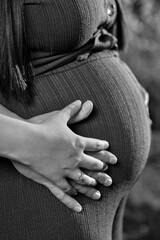 Clasped hands on the belly of a pregnant woman.