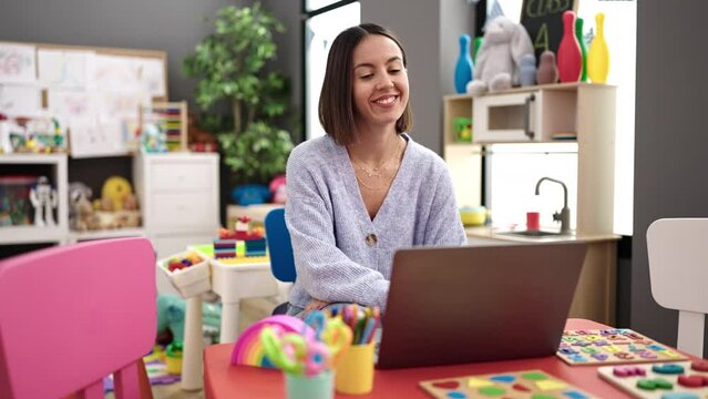 Young beautiful hispanic woman working as a teacher having video call at kindergarten