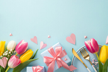 Trendy Mother's day celebration table concept. Top view of plates, cutlery, tulips, gift boxes and decorative hearts on pastel blue background. Perfect for adverts or text
