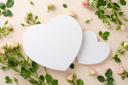 The perfect balance of simplicity and elegance, this top view image of small roses on a pastel beige background includes a spacious area in shape of two hearts for advertisements or branding