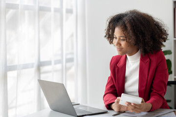 A young American woman is a start-up businesswoman, she sits in the office, managing and running a business from a young generation. Startup business management concept.