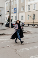 Fototapeta na wymiar a girl in a coat crosses the road