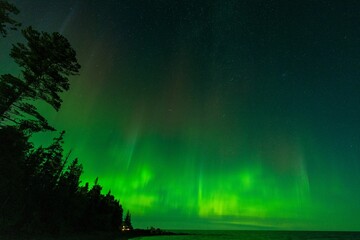 Aurora borealis over the lake surrounded by forest in Keweenaw Peninsula, Michigan