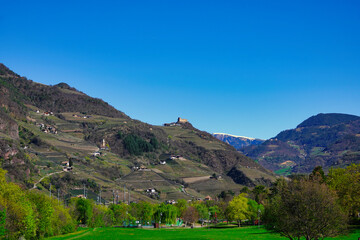 Panoramablick über eine Südtiroler Berglandschaft mit Burgen, Kirchen und Gebäuden am Berghang