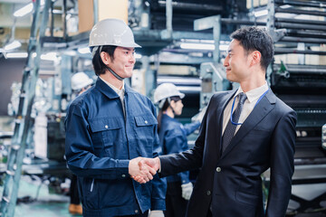 工場で握手をするビジネスマン