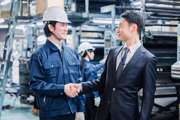 工場で握手をするビジネスマン