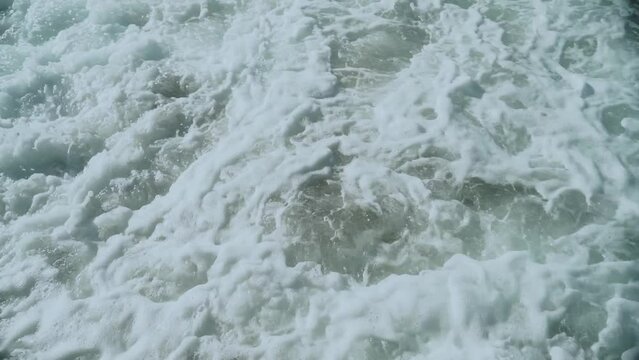 Closed shot. Sea wave with white foam crashing into the pier