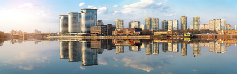 Panoramic view of modern buildings on the river bank in the Moscow district with reflections in the water