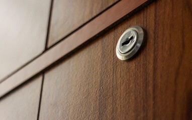 Closeup of a key hole on a drawer door with wooden texture