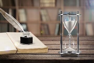 Sand running in old hourglass on wooden table