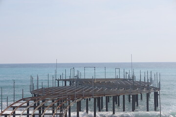 Naklejka premium Storm on the sea, waves of foam against the background of the beach pier, Alanya, December 2023.