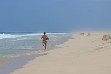 person running on the beach of santa maria on the island of boa vista, in cape verde, african...