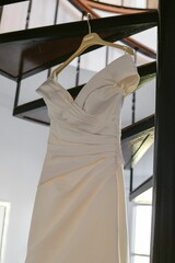 Vertical low angle shot of a white bride dress hung from a spiral staircase