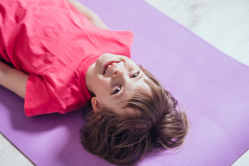 Obraz na płótnie Canvas Tired girl with a smile resting on the mat after a workout. Copy space