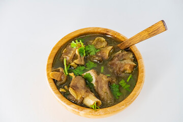 Fresh spicy lamb paya soup in a wooden bowl and ready to eat. Home made mutton soup called paya or attukaal soup in south india. Mutton soup in wooden bowl. Selective focused...